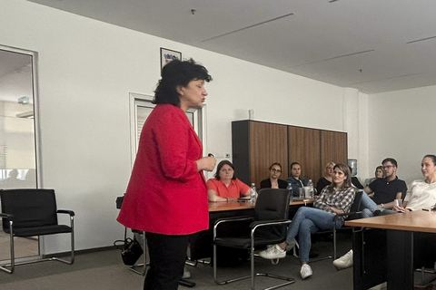 Jasna Rilović stoji i govori pred skupinom polaznika o transparentnosti plaća u poslovnoj dvorani.